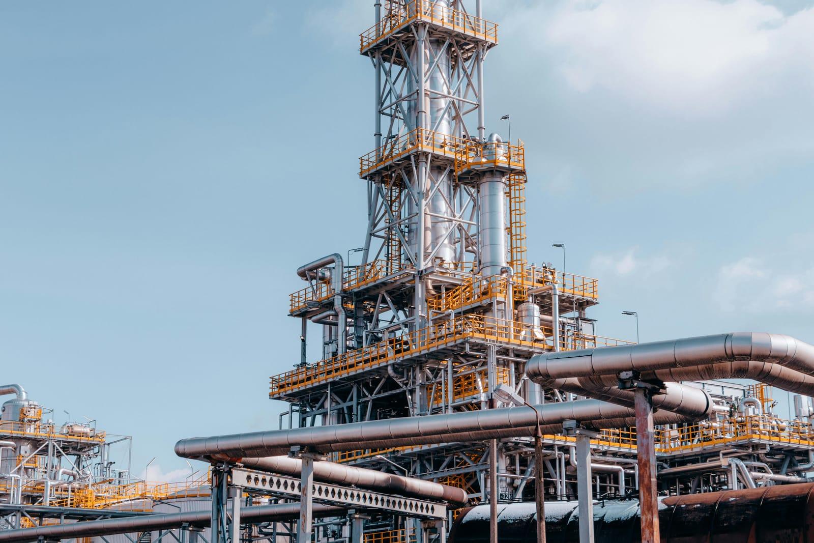 A refinery process tower against a clear sky