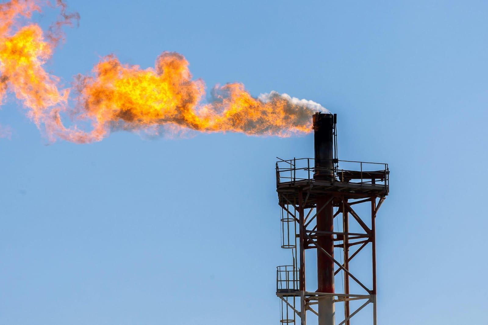 Flare stack burning against a blue sky