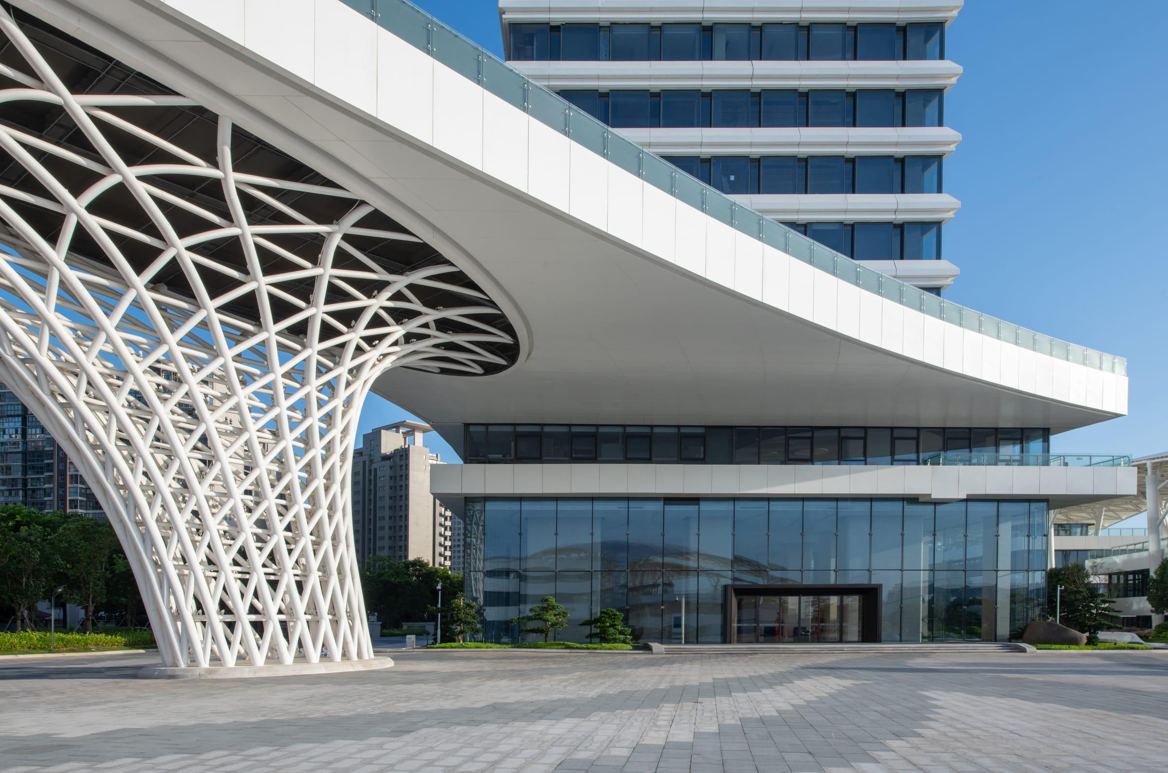 A sweeping white lattice canopy over a modern glass building
